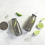 Detox water bottles with chia seeds and lime on a light surface.