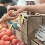Person selecting fresh produce at a market stall.