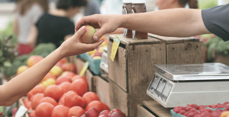 Person selecting fresh produce at a market stall.