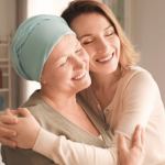 Smiling woman hugging another woman who is wearing a headscarf.