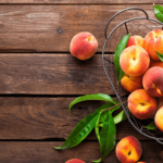 Peaches and green beans on a rustic wooden surface.