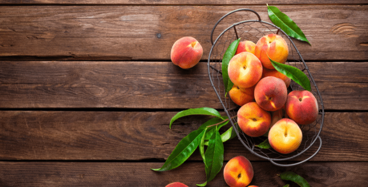 Peaches and green beans on a rustic wooden surface.
