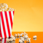 Red-and-white popcorn container with popcorn spilling over.
