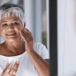 Smiling elderly woman with her hand on her chest.