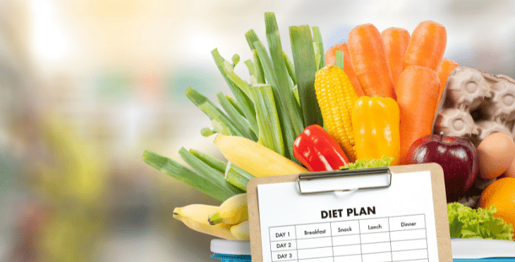 Diet plan clipboard with fresh vegetables in the background.