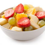 Fruit salad with strawberries and sliced melons in a white bowl.