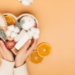 Hands holding skincare products with sliced oranges.