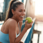 Smiling woman holding an apple after exercising.