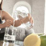 Person pouring water from a glass pitcher.