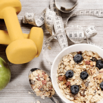 Healthy breakfast with oatmeal, blueberries, and a dumbbell in the background.