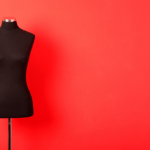 Mannequin in front of a bright red backdrop.