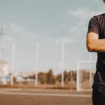 Person standing confidently on a sports field.