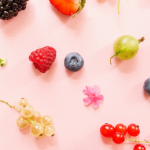 Various colorful fruits and gummies on a pastel background.