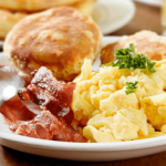 Plate of breakfast food with scrambled eggs, sausage, and biscuits.