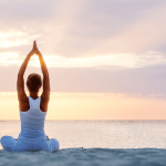 Person doing yoga on the beach at sunrise.