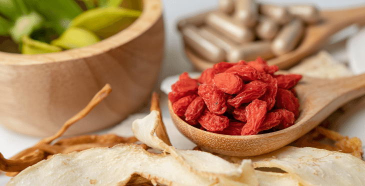 Dried goji berries in a bowl with ginger and lemon.