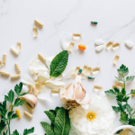 Fresh herbs and white flowers scattered on a white surface.