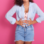Woman holding her stomach with a pink background.
