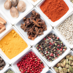 Assorted spices and herbs in white bowls.