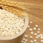 Bowl of oats spilling onto a wooden surface.