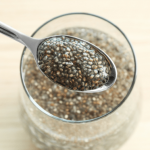 Spoon scooping chia seeds from a glass bowl.