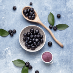 Berries and a wooden spoon on a stone surface.