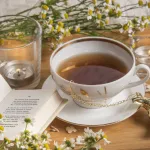 Cup of herbal tea with flowers on a table.