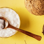 Bowl of yogurt with a wooden spoon on a yellow background.