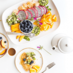 Plate of assorted fresh fruits and vegetables with a cup of tea.